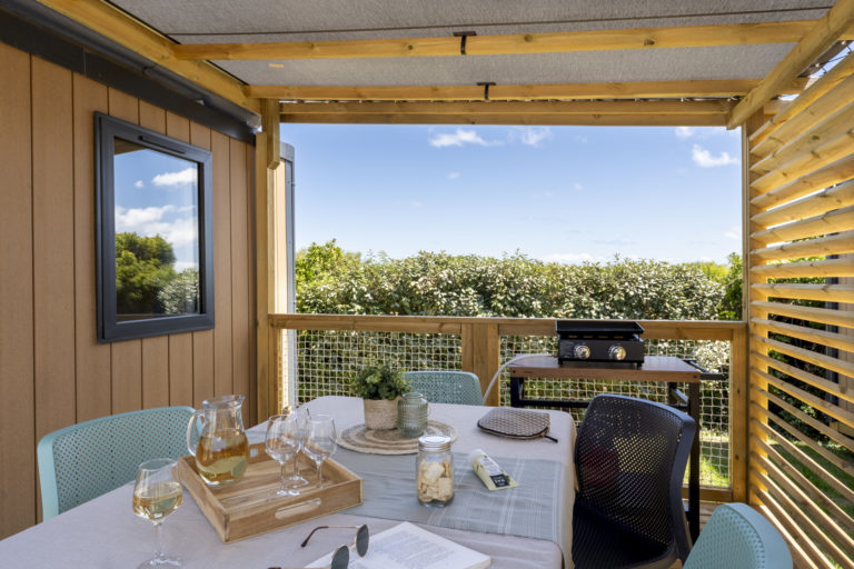 Terrasse ensoleillée avec table et barbecue.