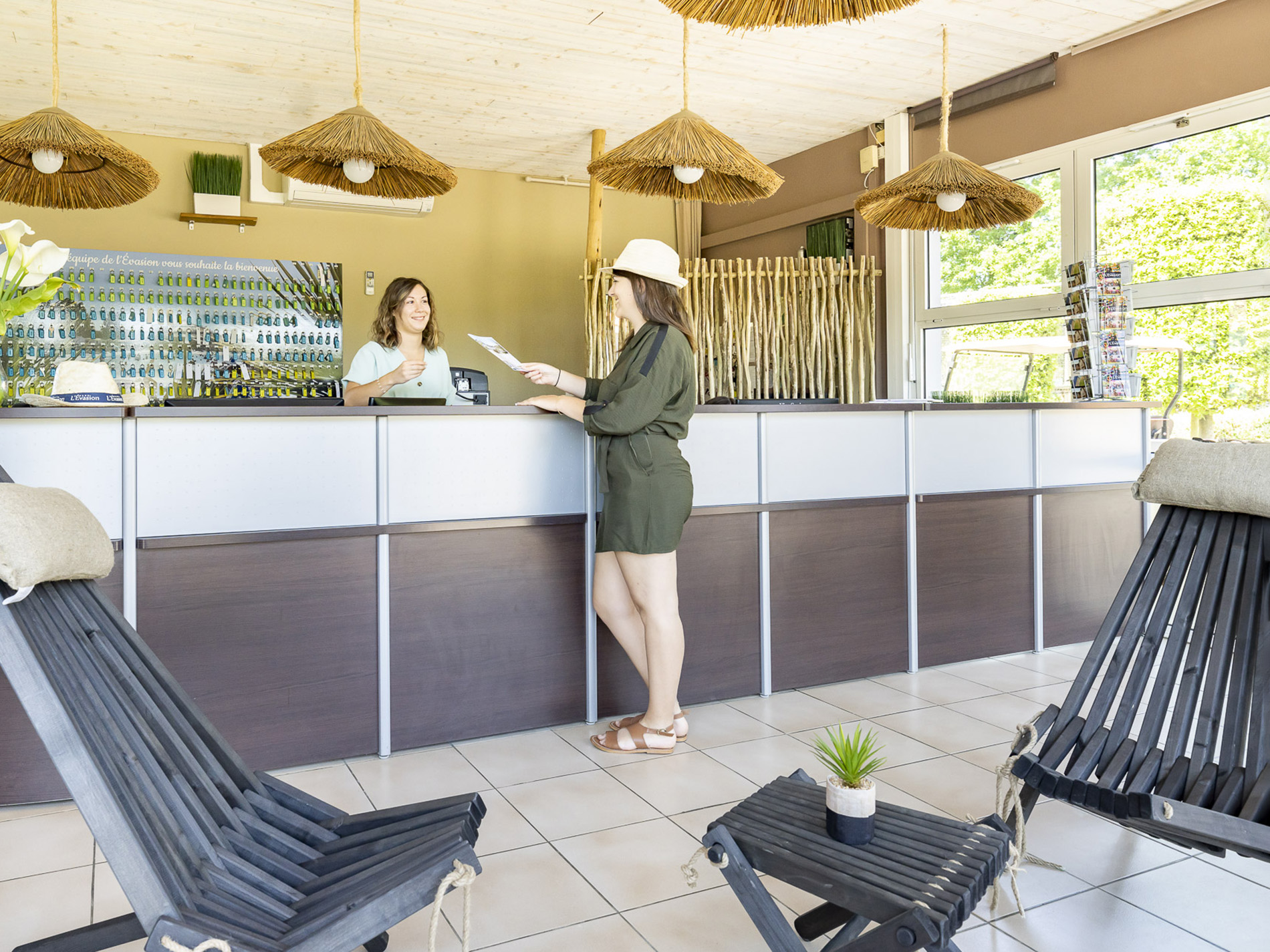 Réceptionniste accueillant une cliente à l'accueil d'un hôtel.