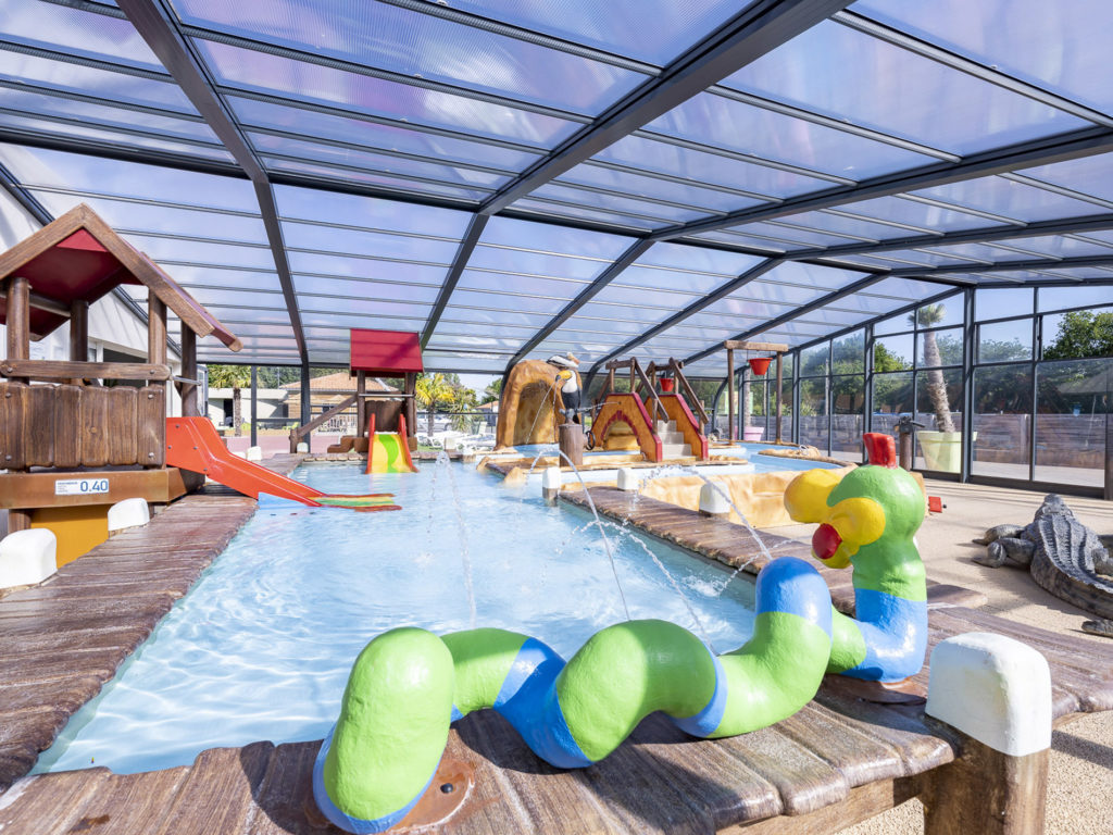 Piscine couverte avec jeux aquatiques colorés.