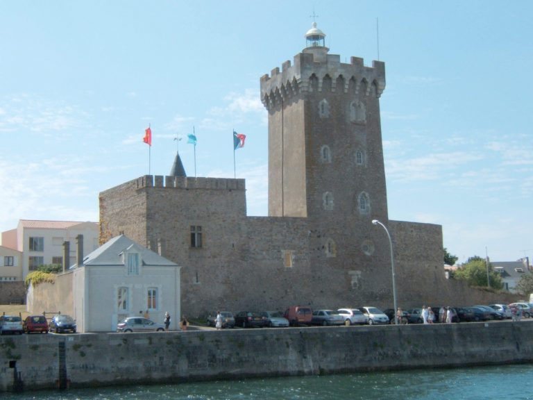 Château médiéval en bord de mer, ciel bleu.